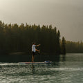 Person paddleboarding on a lake with trees in the background