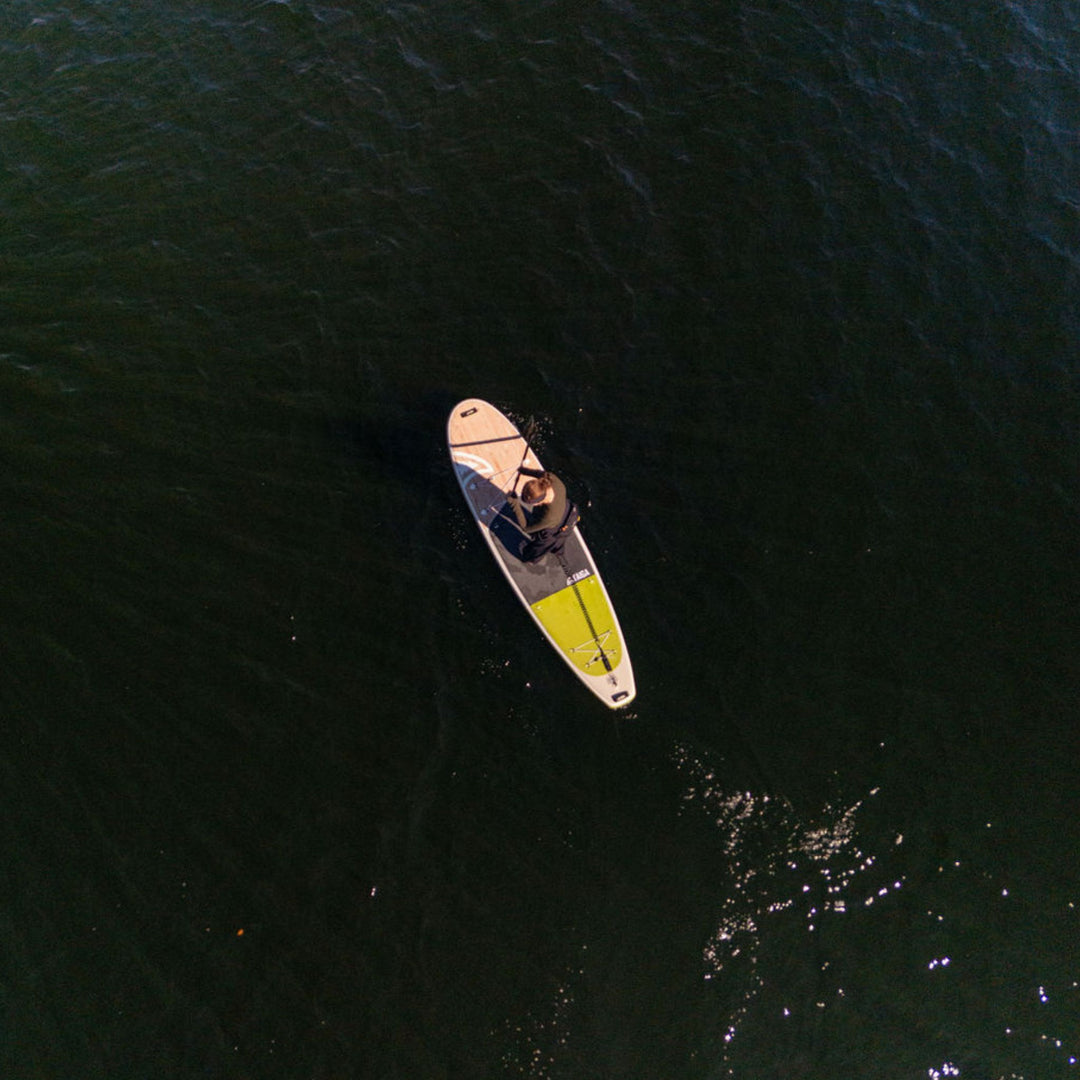Person paddleboarding on dark blue water from an aerial perspective