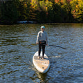 Person standing on a paddleboard, wearing a crewneck with 'Slow Rider Club' text.