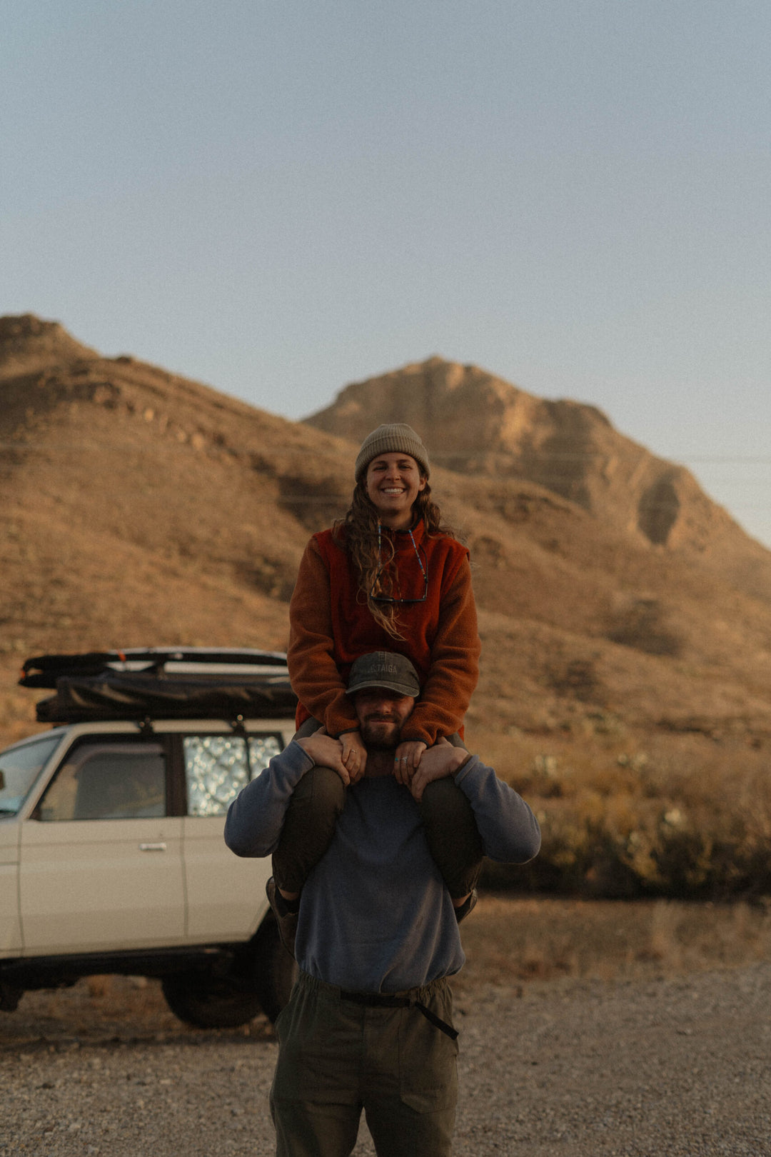 Couple standing in the desert in front of a car