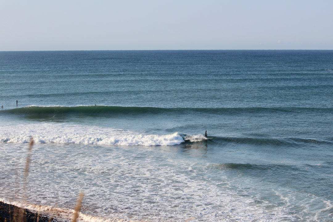 Surfer riding a wave in the ocean with a clear sky