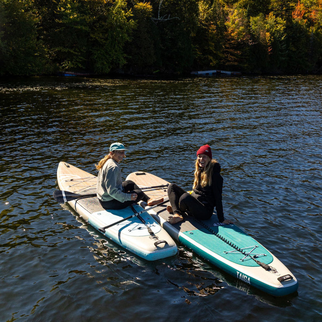Two people on paddleboards in a body of water with trees in the background