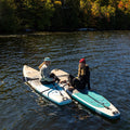 Two people on paddleboards in a body of water with trees in the background