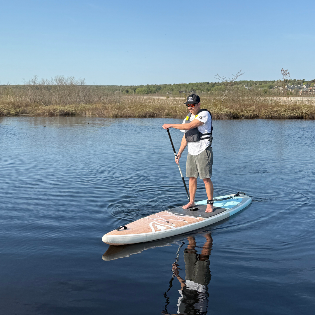 Man paddleboarding on a calm lake with a clear blue sky.
