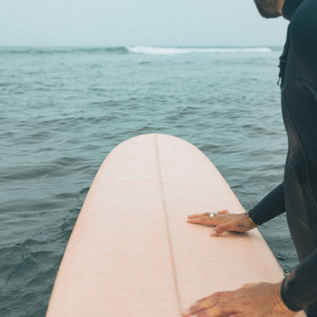 Guy Handling The Longboard Surf Board in The Rosé Color in The Ocean