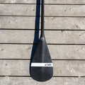 Black paddle on a wooden surface, featuring the Taiga brand.