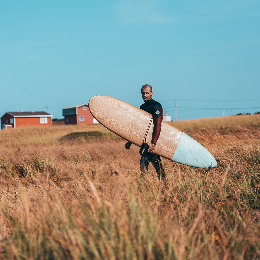 Guy Holding The Malibu Surf Board 7'2" in a Field
