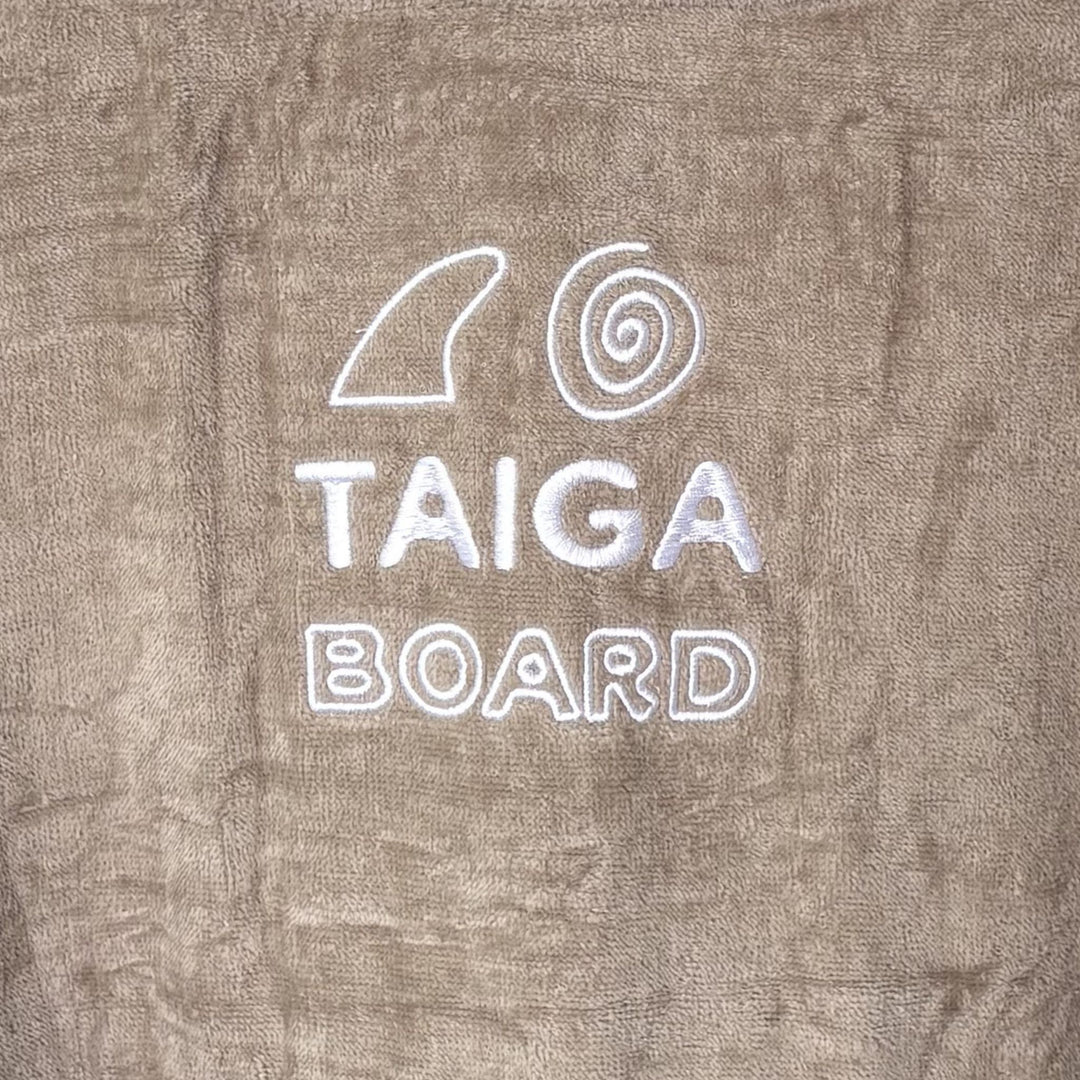 Text 'TAIGA BOARD' on a textured surface with a logo above it.