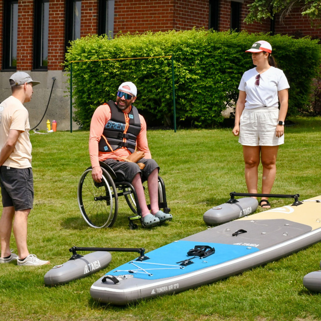 Person in a wheelchair with paddle boards on grass