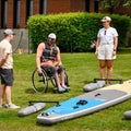 Person in a wheelchair with paddle boards on grass