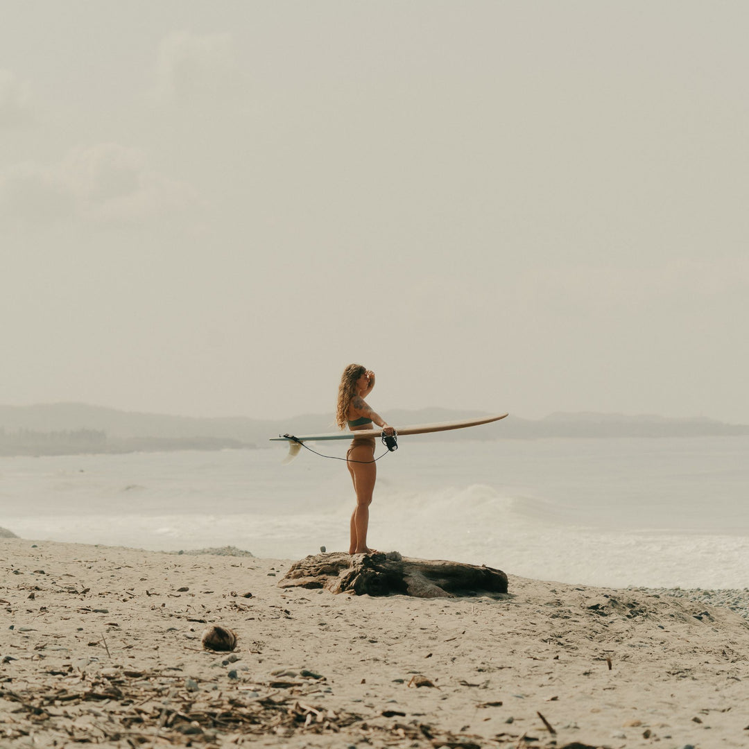 Girl standing with surfboard on hand