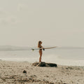 Girl standing with surfboard on hand