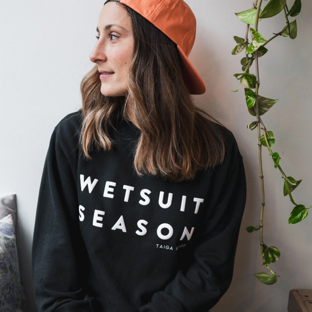 Woman wearing the BLACK WETSUIT SEASON Crewneck by TAIGA BOARD